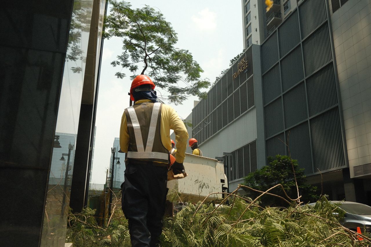 Construction workers in safety gear clearing debris on a sunny day in a Philippine city.